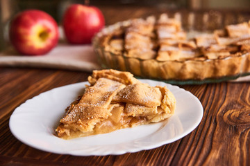 Apple autumn pie with cut slice on the plate on wooden background