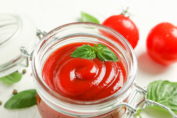 Flat lay composition with fresh tomatoes, basil and sauce in glass jar on white background, space for text and closeup