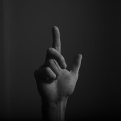 Male hand pointing a finger against a dark background. Selecting, touching