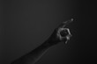 © ink drop - Male hand pointing a finger against a dark background. Selecting, touching
