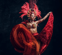 Talented Joyful Can Can Dancer In Red Feather Costume Is Posing At Small Dark Studio.