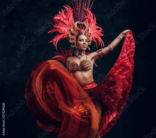 Fotomural Talented joyful can can dancer in red feather costume is posing at small dark studio