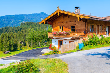 Typical wooden alpine house decorated with flowers on green meadow in Reith village on sunny summer day, Tirol, Austria