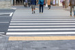 © Nischaporn - People in busy city are walking on the asphalt road on a safety crosswalk on background, Lifestyle in Japan