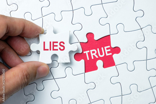 Fotografía True word on missing puzzle with a hand hold a piece of lies word puzzle