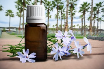 Poster - Spa oil in bottle and  flowers on wooden desk