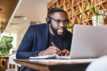 Just start. Young businessman with headphones sitting in cafe in front of laptop and networking