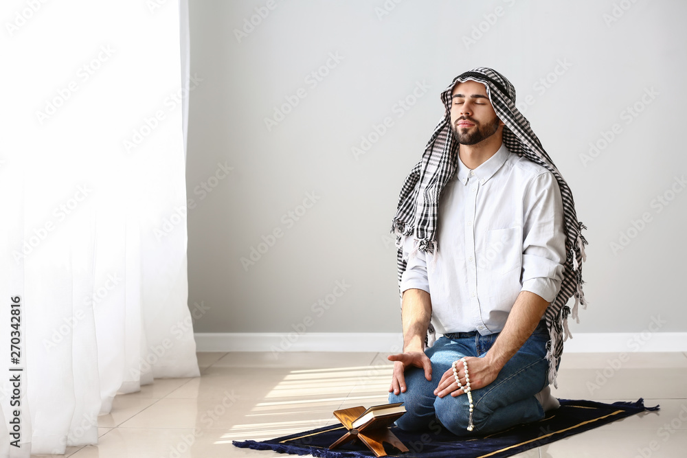 Young Muslim man praying indoors
