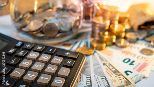 Fotomural Calculator with currency glass jar and gold coins stack, dollar and euro banknotes on the table