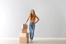 Young Woman With Cardboard Boxes Near Light Wall