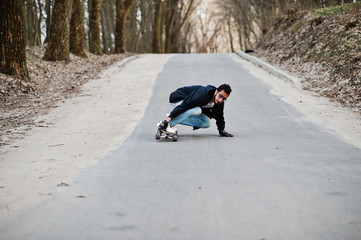 Wall Mural - Street style arab man in eyeglasses with longboard longboarding down the road.