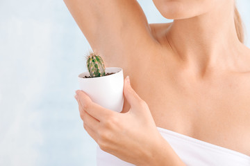 Sticker - Beautiful young woman with cactus on light background. Depilation concept