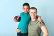 © Pixel-Shot - Happy father and little adopted boy with rugby ball on color background