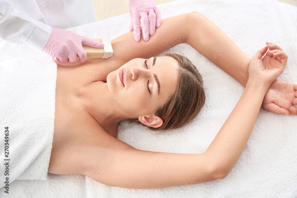 Young woman undergoing armpits epilation in beauty salon