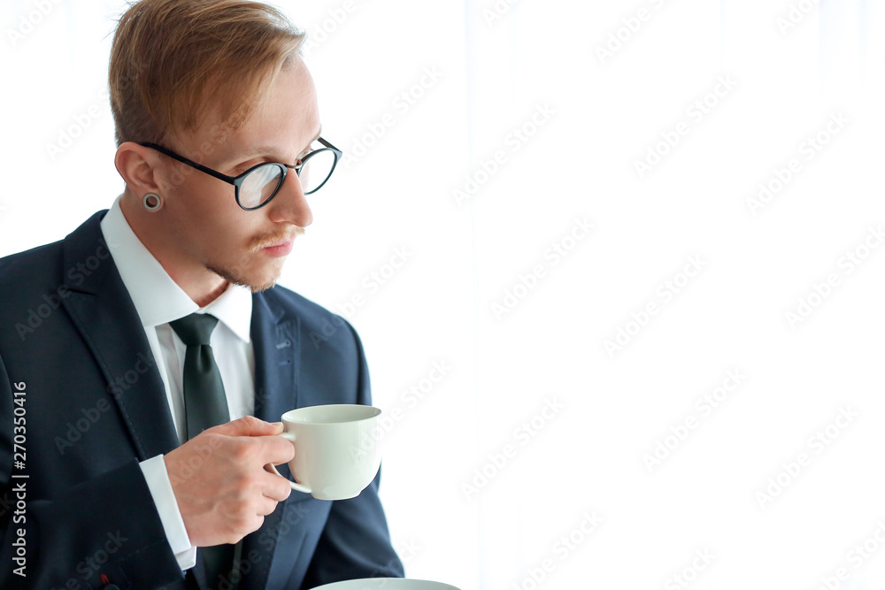 Handsome businessman drinking coffee near window