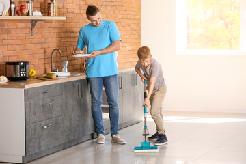 Father and son cleaning kitchen together