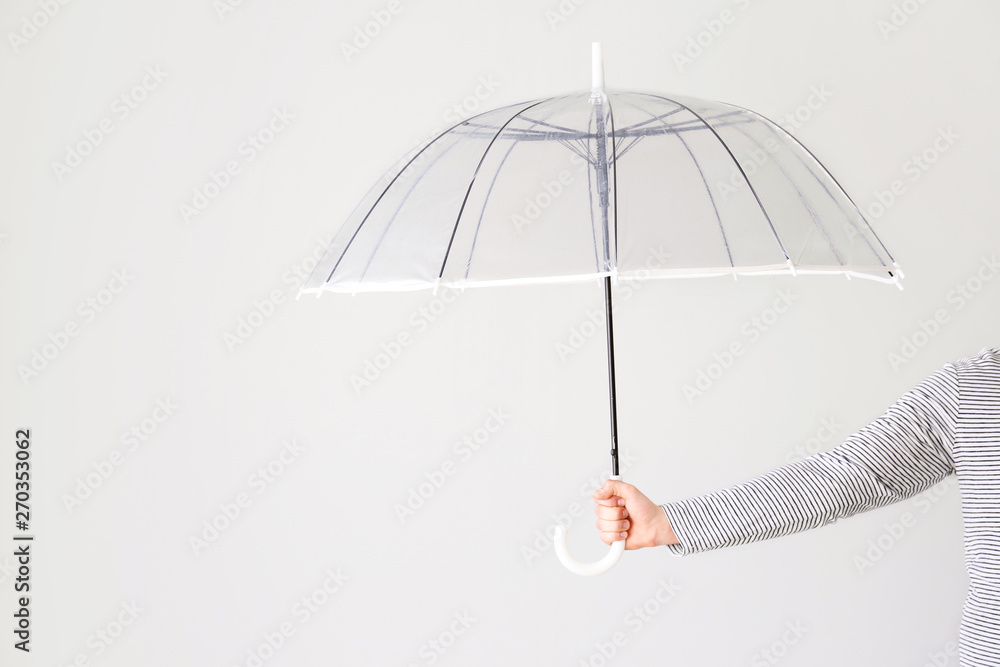 Female hand with stylish umbrella on light background