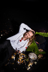 happy and drunk man smiling with closed eyes and sitting near african american man and confetti of black