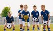 © matimix - Young players of soccer team lift up the golden cup trophy after winning the final soccer match. Children celebrate success in sports