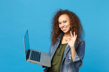 young african american girl teen student in denim clothes, backpack work on pc isolated on blue wall