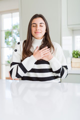 Poster - Beautiful young woman wearing stripes sweater smiling with hands on chest with closed eyes and grateful gesture on face. Health concept.