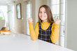 © Krakenimages.com - Beautiful young girl kid sitting on the table celebrating surprised and amazed for success with arms raised and open eyes. Winner concept.