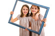 © _jure - Identical twin girls are making happy expressions with picture frame.