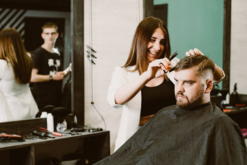 Canvas Print - the barber cuts a bearded man with scissors in the salon