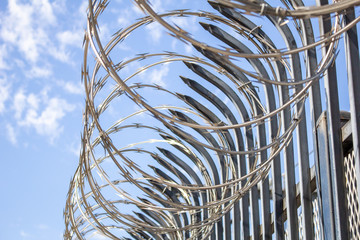 Barbed wire loops on the perimeter of a sharp metal fence