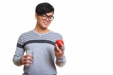 Happy Asian man smiling and looking at red apple while holding g