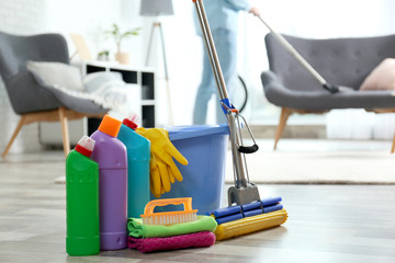 Wall Mural - Detergents, bucket and mop on floor with janitor vacuuming carpet indoors