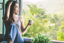 Beautiful Asian Woman Sitting Next To The Window Drinking Coffee And Relaxing With Beautiful Nature View 