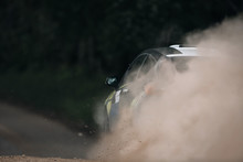Rally Car Make A Turn With The Clouds Of Sands And Dust. Fast Moving Sport Car Makes A Lot Of Dust