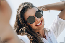 Smiling Young Woman In Sunglasses Holding Camera And Smiling Make Selfie Recording Video Vlog From Hands With Mirrorless Camera On The Beach.Making Vlog, Blogger Beauty Business Concept. 