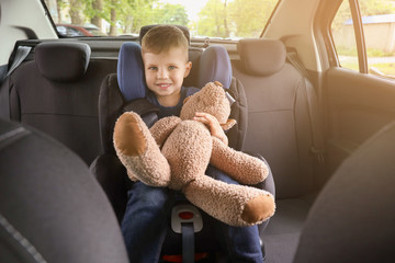 Canvas Print - Little boy with toy bear buckled in car seat