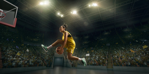 Female basketball player makes slam dunk. Basketball player on big professional arena during the game