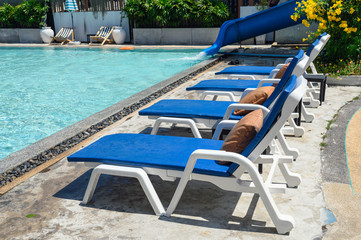 Blue sunbeds with mattress on side of swimming pool