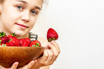 A young woman is holding a bowl of strawberries