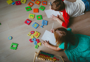 Wall Mural - little boy and girl learn to write and calculate numbers