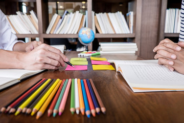 High school or college student group sitting at desk in library studying and reading, doing homework and lesson practice preparing exam to entrance, education concept