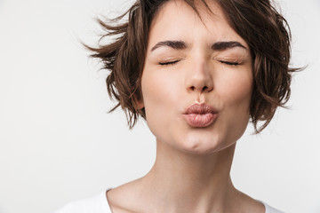 Canvas Print - Portrait closeup of attractive woman with short brown hair in basic t-shirt making kiss face at camera