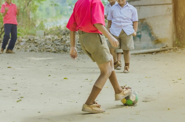 Wall Mural - Student enjoy to play the old football with his friends on the ground in school.