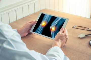 Wall Mural - Doctor holding a digital tablet with x-ray of legs with pain on the knees