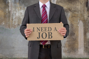 Businessman holding card with the words I NEED A JOB