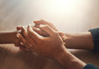 © StratfordProductions - Couple's hand holding hands on wooden desk
