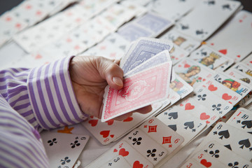 Wall Mural - Closeup of wrinkled hands of senior lady playing solitaire