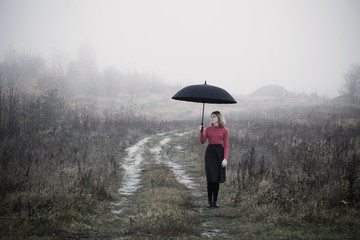 Wall Mural - young girl with umbrella in autumn field