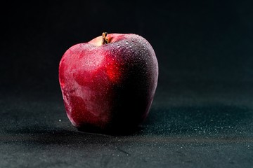 fresh and delicious red apple isolated against black background, with water droplets on the apple, selective focus