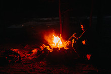 Man Stoking Campfire At Night