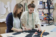 © evelinphoto - Seamstresses measure the fabric for sewing a dress in the atelier. Two female tailor working in in the sewing workshop.